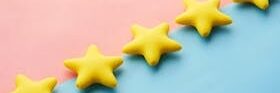 Yellow stars on pink and blue pastel background for rating or review concept.